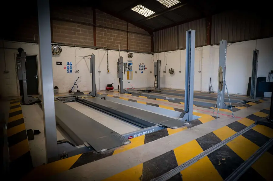An empty vehicle test lane at My Car Import, with lifts and yellow and black floor markings